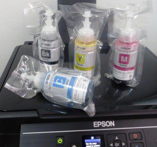 The printer is packaged with Cyan, Magenta, Yellow, and Black ink bottles that the user must carefully fill the tanks with.