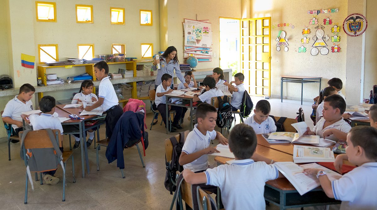 A typical Escuela Nueva classroom, featuring students within two grade levels sitting in group desks and actively discussing their lessons. (Credit: Jared Wade)