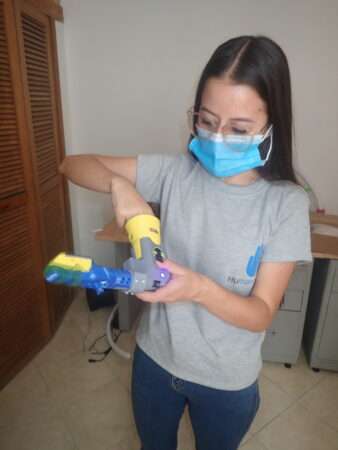 Intern Sara Patiño adjusts a robotically enhanced Batman-themed prosthetic arm