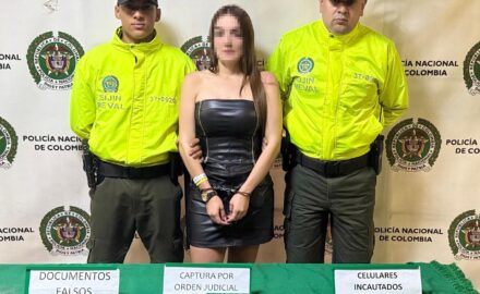 Front photo of the 'Scopolamine Queen of Lleras Park', handcuffed, with two police officers on each side