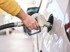 A driver filling up at their tank at the gas pump.