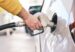 A driver filling up at their tank at the gas pump.
