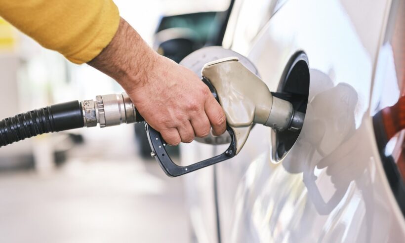 A driver filling up at their tank at the gas pump.