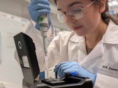 Colombian scientist Laura Gonzalez Garcia working in a laboratory, carefully using a pipette with specialized equipment while wearing a lab coat, gloves, and safety glasses. (Photo: Colombia Embassy US via Instagram)