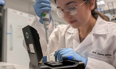 Colombian scientist Laura Gonzalez Garcia working in a laboratory, carefully using a pipette with specialized equipment while wearing a lab coat, gloves, and safety glasses. (Photo: Colombia Embassy US via Instagram)