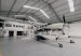 A large white amphibious seaplane (Cessna Caravan-type aircraft with floats) is parked inside a spacious modern hangar. (Photo: Alma Air)