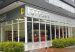 A modern glass Ferrari showroom with the iconic Ferrari logo and red sports cars visible inside, along with the landscaped entrance in Bogotá. (Photo: EEIM via Wikimedia Commons)