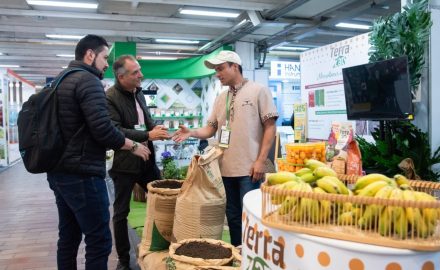 Exhibitors and visitors networking at a Terra Zan booth during Expo Agrofuturo, featuring agricultural products including bananas, soil amendments, and fertilizer displays. (Photo : Expo Agrofuturo)