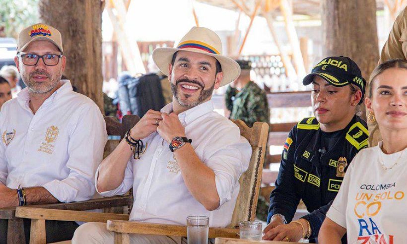 President Abelardo de la Espriella, in a white hat and a shirt embroidered with his title, seated among officials