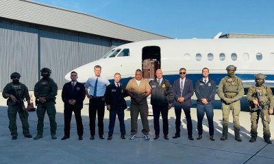 Geovany Andrés Rojas, alias Araña, stands among US law enforcement officials in front of a jet