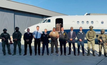 Geovany Andrés Rojas, alias Araña, stands among US law enforcement officials in front of a jet