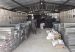 Metal trays of drill core are stacked in rows inside a storage shed while two workers sweep and tidy the floor.