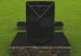 Black marble memorial monolith on a stone base in a grass field