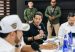 Commerce, Industry and Tourism Minister Mauricio Gómez Amín speaks into a microphone as a military officer stands guard behind him.