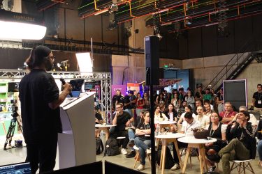 A speaker addresses a seated audience during an academic-program session at Cinemotion Labs in Medellín.