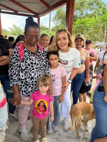 Mónica Gil Ryan poses with an older woman, two young girls and neighbors under a covered community space