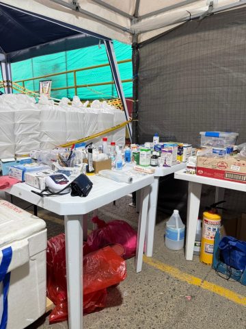 Tables of over-the-counter medicines, a blood pressure monitor and first-aid supplies inside a relief tent
