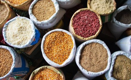 Open sacks of corn, red beans, rice and other grains viewed from above at a market