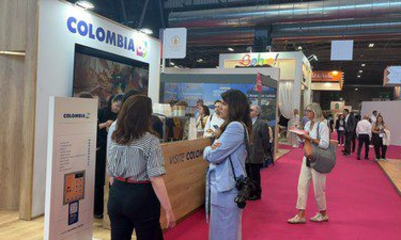 People gather at the Colombia booth's coffee counter, marked Visite Colombia,