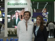 Daniel Mitchell in a white Acoplásticos vest and Ana Garibello in a dark blazer standing at a plastics trade fair booth