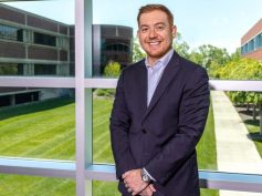 Edwin Urrego, executive loan officer at Kennedy Funding, standing at a window overlooking an office campus.