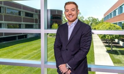 Edwin Urrego, executive loan officer at Kennedy Funding, standing at a window overlooking an office campus.