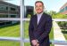Edwin Urrego, executive loan officer at Kennedy Funding, standing at a window overlooking an office campus.