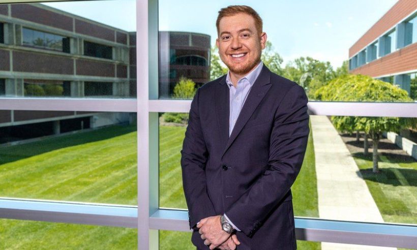 Edwin Urrego, executive loan officer at Kennedy Funding, standing at a window overlooking an office campus.