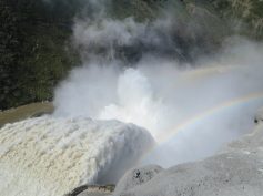 Water and mist pour through the spillway of the Hidroituango hydroelectric dam, with a rainbow in the spray