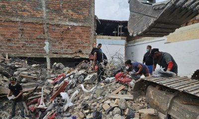 An excavator clears rubble as volunteers search the wreckage of a collapsed plastic bag factory in Pereira.