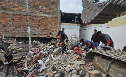 An excavator clears rubble as volunteers search the wreckage of a collapsed plastic bag factory in Pereira.