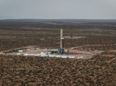 Aerial view of a drilling rig on a cleared well pad surrounded by scrubland in Vaca Muerta, Argentina