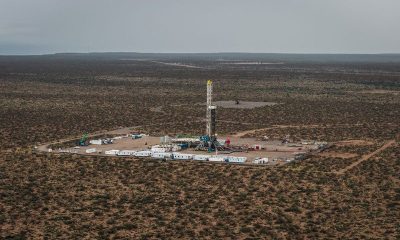 Aerial view of a drilling rig on a cleared well pad surrounded by scrubland in Vaca Muerta, Argentina