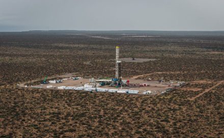 Aerial view of a drilling rig on a cleared well pad surrounded by scrubland in Vaca Muerta, Argentina