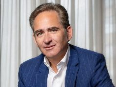 Portrait of Joaquín Gutiérrez Caballero in a blue pinstripe blazer and white shirt in front of light curtains