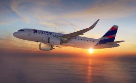 A LATAM Airlines Airbus A320neo banking in flight over the ocean at sunset, with clouds in the sky.