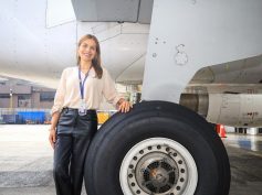 Erika Zarante smiles with one hand on the main landing gear tire of a LATAM aircraft on the airport ramp.