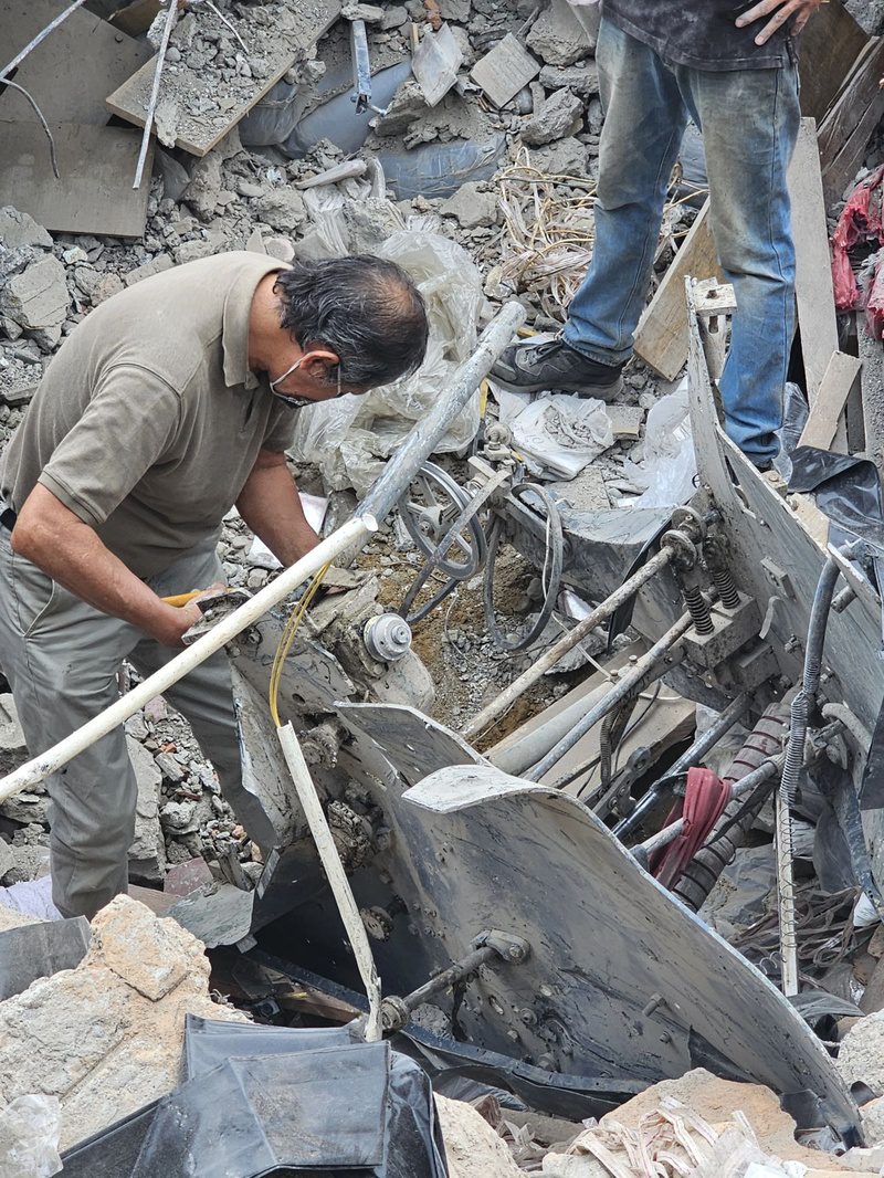A man examines damaged machinery buried in the rubble of the collapsed plastic bag factory.