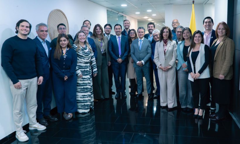 About 20 tourism guild representatives and MinCIT officials pose in a hallway beside a Colombian flag