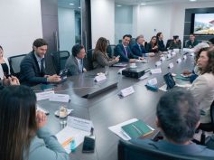 Tourism guild representatives and ministry officials seated around a long conference table with a screen showing a rural scene