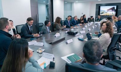 Tourism guild representatives and ministry officials seated around a long conference table with a screen showing a rural scene
