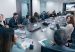 Tourism guild representatives and ministry officials seated around a long conference table with a screen showing a rural scene