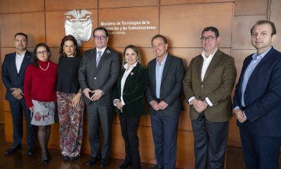 Colombia's ICT and Justice ministers pose with mobile carrier representatives in front of a MinTIC sign in Bogotá.