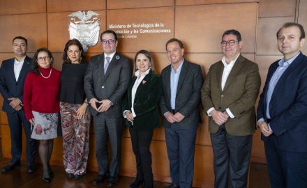 Colombia's ICT and Justice ministers pose with mobile carrier representatives in front of a MinTIC sign in Bogotá.