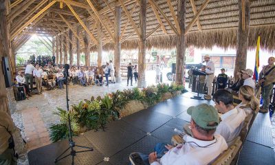 A speaker at a podium addresses an audience under a thatched open-air pavilion in Quimbaya, Quindío
