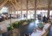 A speaker at a podium addresses an audience under a thatched open-air pavilion in Quimbaya, Quindío