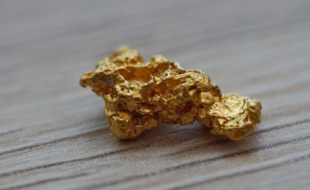 Raw gold nugget on a wooden surface
