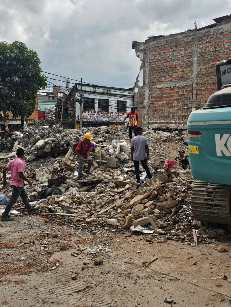 Residents pick through rubble outside a demolition site marked Recuperamos Ospina in Pereira.