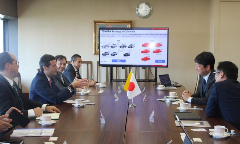Delegates at a conference table beneath a screen showing a slide titled Toyota Strategy in Colombia with 2026 and 2027 vehicle lineups