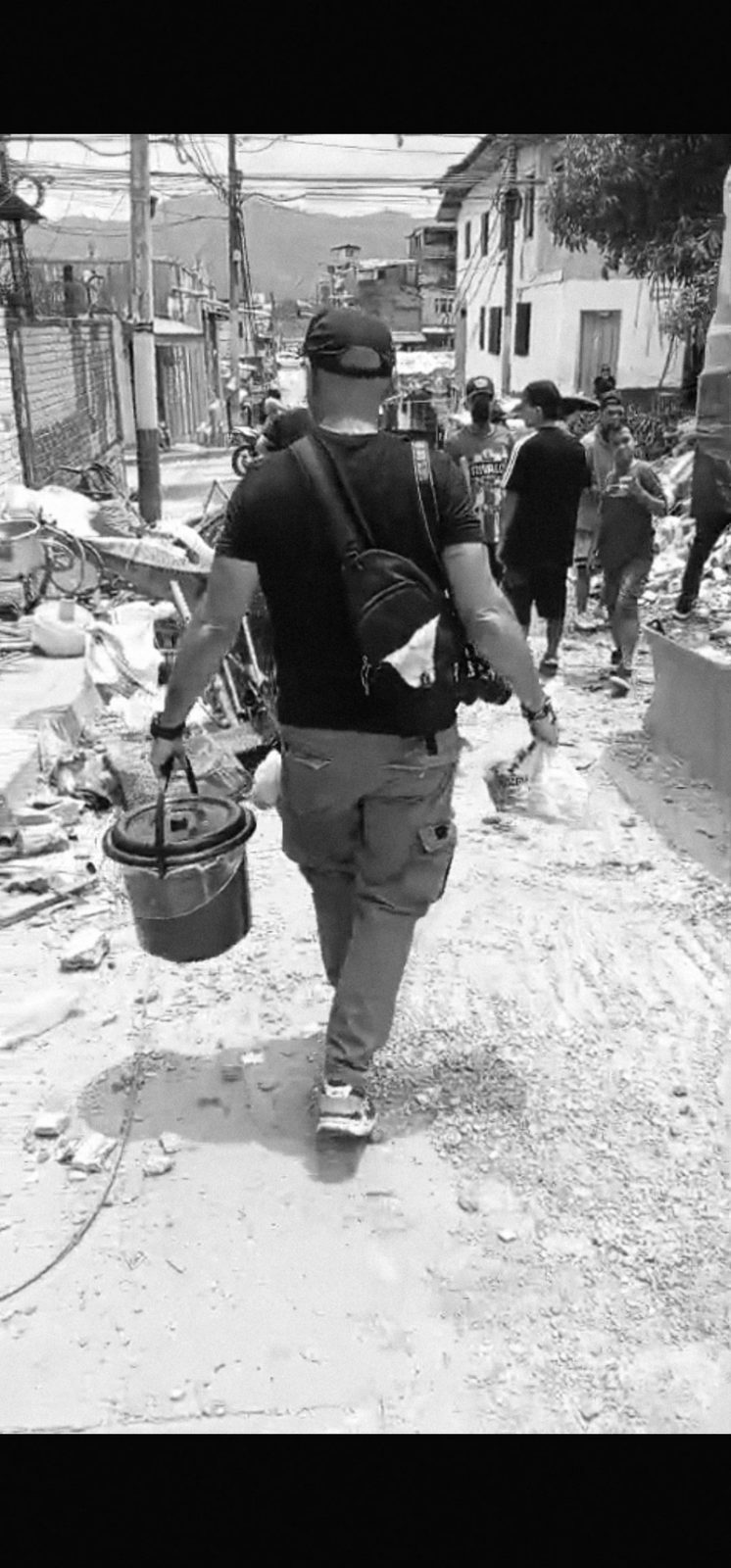A volunteer carries supplies down a debris-covered street in the earthquake zone.